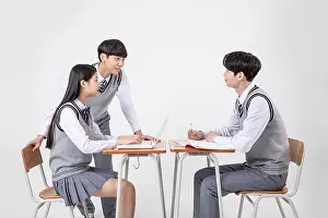 Studying Prints: A group of students in school uniforms work together on a laptop in a classroom
