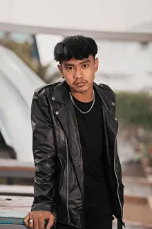 Rebellion Prints: a grown man in a black leather suit and chain necklace posing very dashingly in the broad daylight
