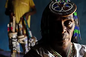 Guji woman in traditional dress + decorated water containers in the background ( Ethiopia)