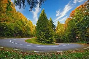 Images Dated 12th October 2019: A hairpin in a mountain road in autumn colored forest at sunrise
