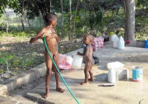 Haiti Prints: Haitian children washing themselves outdoors with a hose pipe