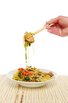 Noodles Prints: Hand holding chopsticks with Singapore noodles above a bowl against a white background