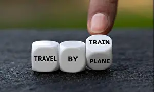 Hand turns dice and changes the expression travel by plane to travel by train