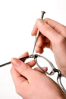 Repairing Prints: two hands fixing pair of eye glasses with small screwdriver