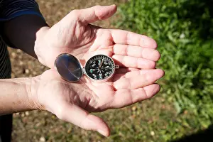 Compass Prints: hands of old woman with compass on green lawn