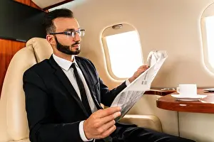 Business Class Prints: Handsome businessman wearing elegant suit flying on exclusive private jet - Successful entrepreneur sitting