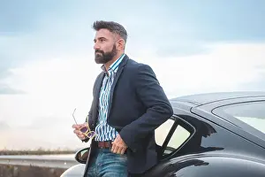 A handsome elegant male leaning on his sports car