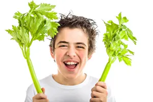 Vest Prints: Handsome hispanic boy with soft skin in white long sleeved t-shirt is smiling while holding green celery sticks with
