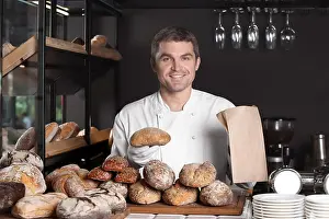 Freshly Prints: Handsome man with freshly baked bread working in bakery shop
