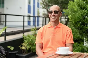 Latino Prints: Handsome middle aged Italian bald man face in orange polo shirt sitting at cafe table outdoors wearing sunglasses