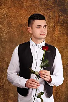 Valentines Day Prints: Handsome pensive guy in a black vest with a rose in his hands on valentine's day