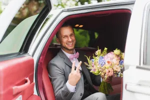 Newlywed Prints: Handsome stylish groom with bouquet in the wedding car. A man in a suit with a bow tie