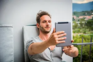Concentrating Prints: Handsome trendy man wearing t-shirt sitting and doing videochat