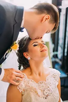 Forehead Prints: Handsome young groom kissing his beautiful bride before honeymoon