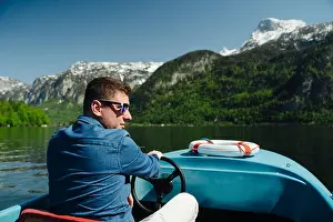 Motorboat Prints: Handsome young guy controls a motorboat on a mountain lake