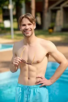 Real Life Prints: A handsome young man in blue shorts standing at the swimming pool