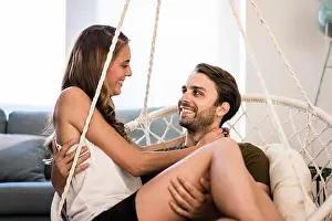 Embracing Prints: Happy affectionate couple embracing in hanging chair at home