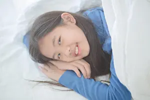 Awake Prints: Happy Asian girl lying on the bed with sun light on lazy day