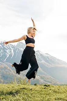 Practicing Prints: Happy blond woman with hand raised dancing over meadow
