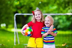 Preschooler Prints: Two happy children playing European football outdoors in school yard