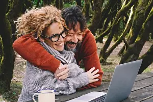 Happy couple in love and friendship enjoy video call on laptop together hugging and smiling. Nature outdoors forest background