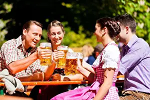 Two happy couple sitting in Bavarian Beer garden and enjoy the beer and the sun
