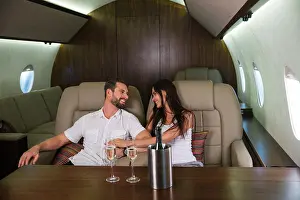 Roaming Prints: Happy couple travelling on a luxury private jet - Young adults travel on a first class flight