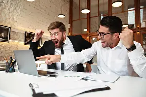 Formalwear Prints: Two happy entrepreneurs looking at laptop screen celebrating success in office