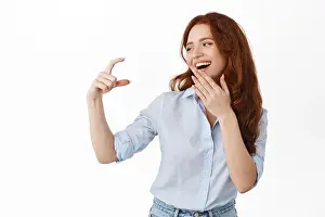 Redhead Prints: Happy female model looking at small tiny thing