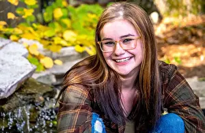 Casual Attire Prints: Happy girl poses for a senior photo in a flannel shirt and torn jeans