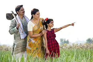 Happy Indian family in agricultural field looking away