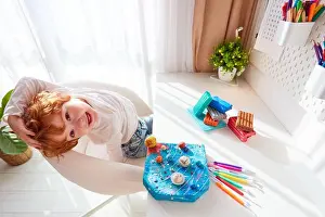 Planet Earth Prints: happy kid sitting at the desk with handcrafted solar system, made of modeling plasticine