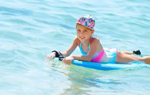 Surfboard Prints: Happy little girl with bodyboard in blue transparent sea