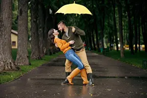 Beautiful Girl Prints: Happy love couple dancing in park in summer rainy day