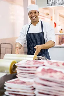 Stretch Prints: happy male butcher wrapping meat in butchery