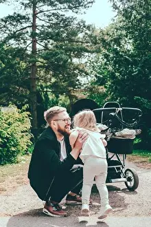 Love Emotion Prints: Happy man crouching while holding daughter by baby carriage on footpath at park