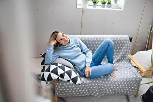 Dreaming Prints: Happy mature woman sitting on sofa in attic