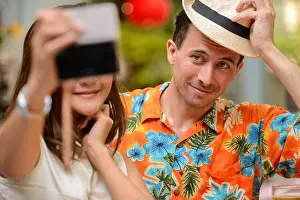 Vlogger Prints: Happy multi ethnic tourist couple taking selfie together at restaurant