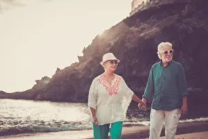 Forever Prints: happy senior adult couple in love waing and smiling enjoying the summer time on the beach