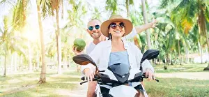 Honeymoon Prints: Happy smiling couple travelers riding motorbike scooter under palm trees