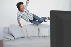 Casuals Prints: Happy soccer fan cheering while watching tv