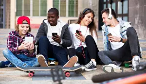 Texting Prints: Happy teens playing on smarthphones and listening to music