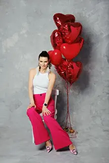Tank Top Prints: Happy woman in white tank top and wide pink trousers sitting on chair next to balloons