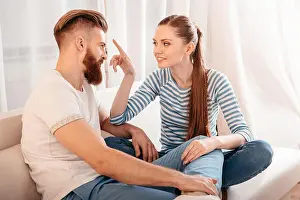 Closeness Prints: Happy young couple sitting together on sofa and looking at each other