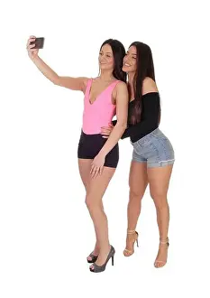 Girlish Prints: Two happy young slim women standing in the studio in shorts and high heels