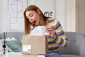 Parcel Prints: Happy young woman opening parcel at home