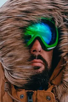Goggles Prints: Headshot photo of a man in a cold snowy area wearing a thick brown winter jacket