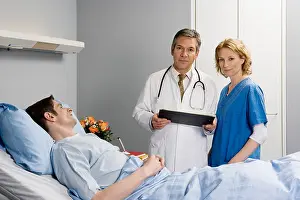 Color Photography Prints: Two healthcare workers standing next to a patient in bed