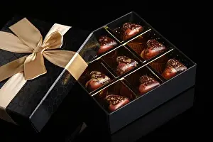 Candies Prints: Heart shaped painted luxury handmade bonbons in a gift box on a black background