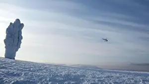 Helicopter flying above snow covered forest on a blue ske background. Clip. Natural frosty winter background